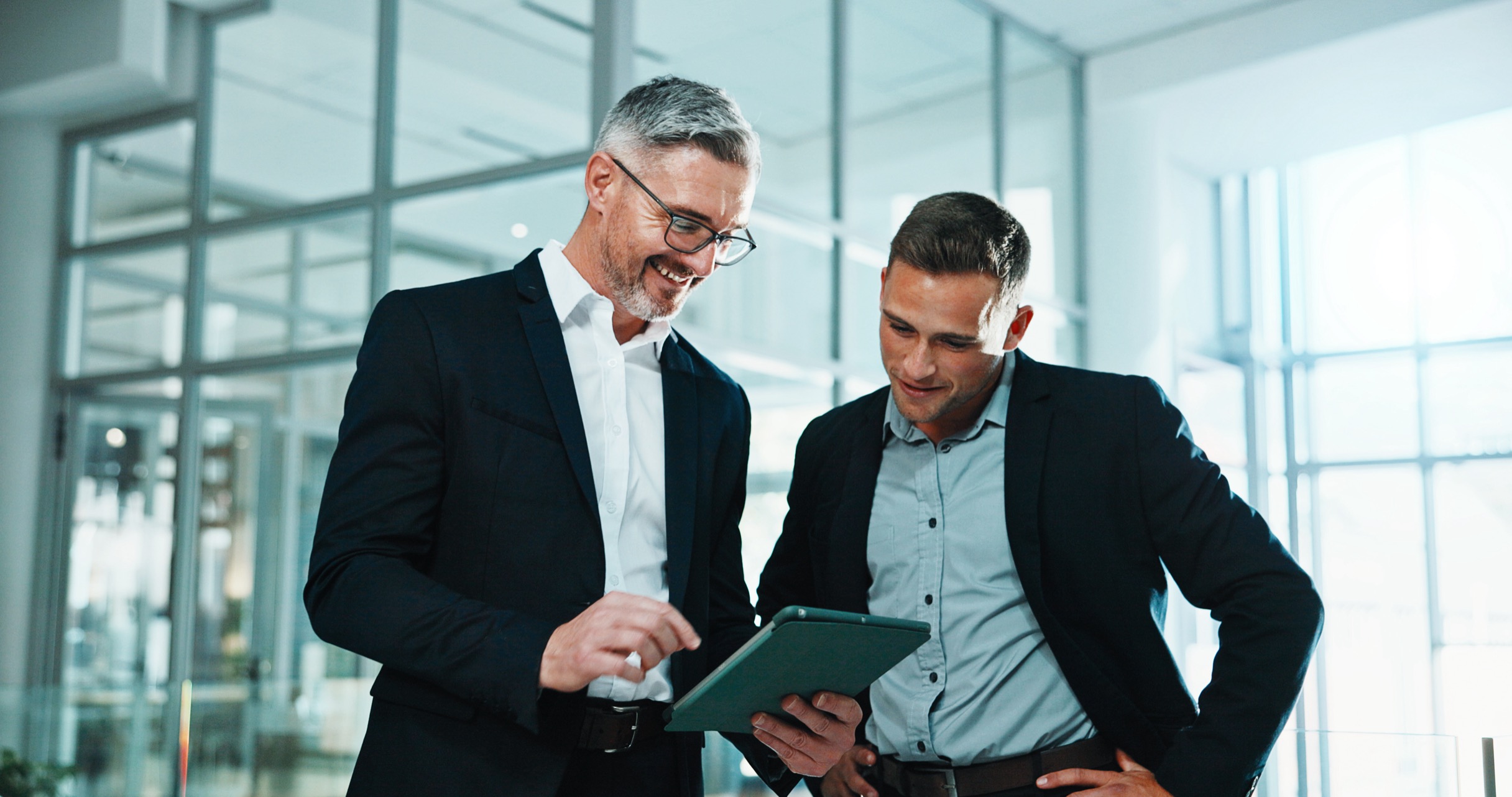 Two advisers reviewing an investment plan on a tablet in a bright office