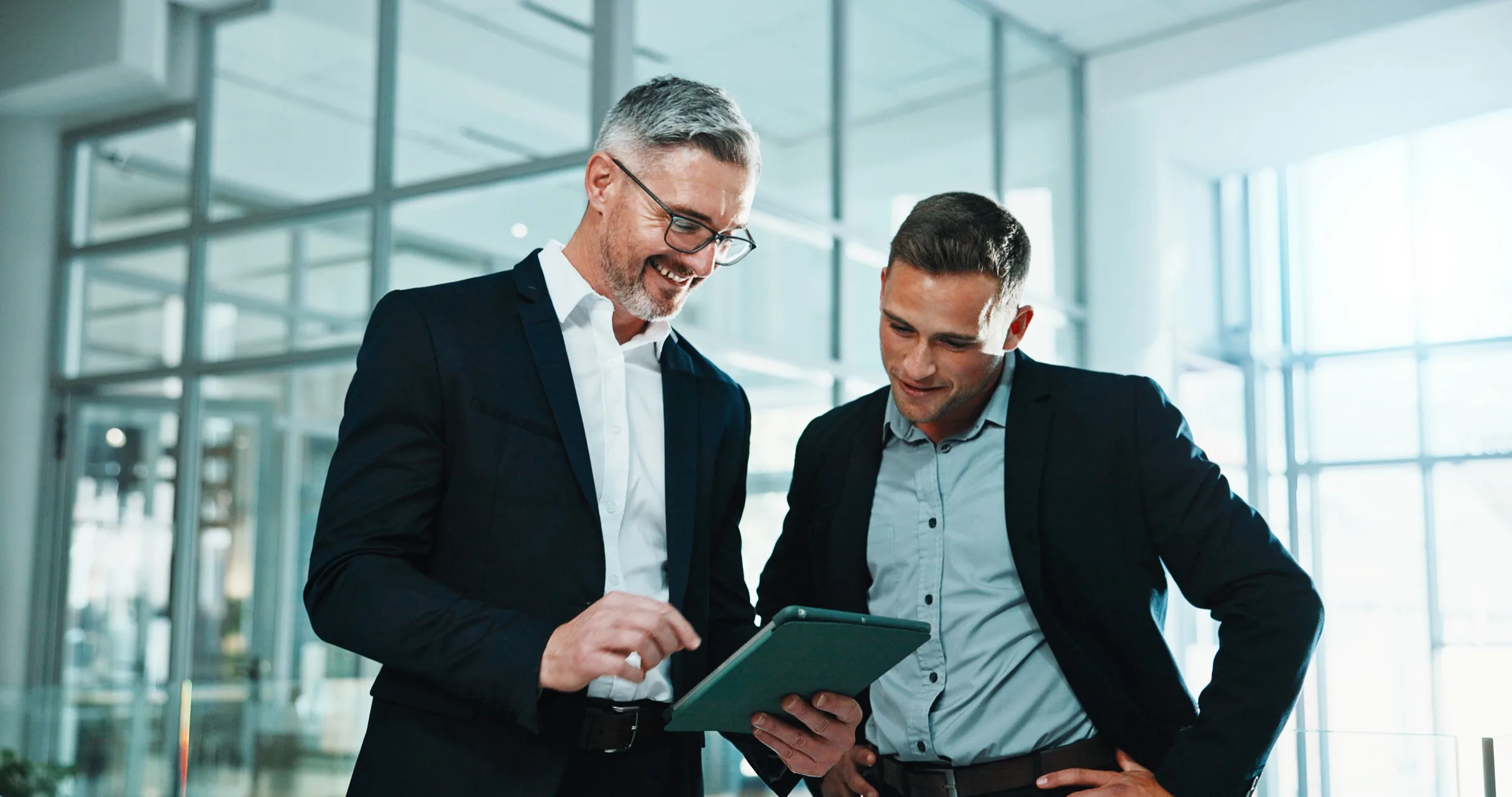 Two advisers reviewing an investment plan on a tablet in a bright office